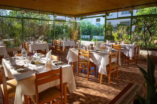 a restaurant with white tables and chairs and windows at Hotel El Abuelo in Carhuaz