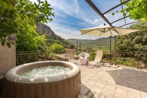 a hot tub sitting on a patio with an umbrella at Under the rock house in Osp with jacuzzi in Osp