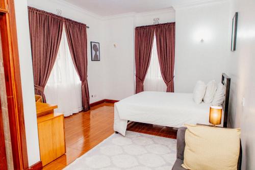 Un dormitorio con una cama y dos ventanas en Baraa House Arusha, en Arusha