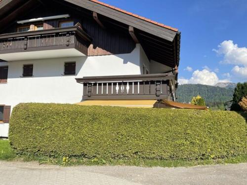 a house with a hedge in front of a building at Holiday apartment Bergzeit, Allgäublick Steibis in Steibis