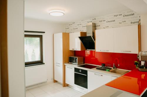 a kitchen with red and white cabinets and a microwave at CABANA BERNER stațiunea Mogoșa in Baia-Sprie