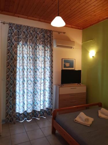 a room with a bed and a tv and a window at MARATHES STUDIOS in Agios Nikitas