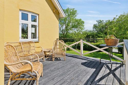 a deck with wicker chairs and a table on a house at Beautiful Yellow Country Villa By The Water in Millinge