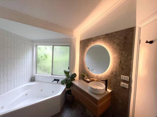 Un baño con bañera, lavabo y espejo. en Tropical Getaway, en Kororo Basin