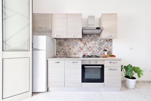 a kitchen with white cabinets and a white refrigerator at LuEDa House - Trasfertisti e Turisti in Surbo