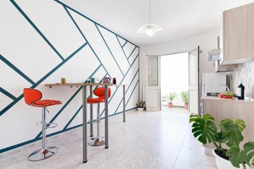 a kitchen with a table and two red chairs at LuEDa House - Trasfertisti e Turisti in Surbo