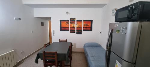 a kitchen with a refrigerator and a table and a couch at Complejo Boulevard Plottier in Plottier