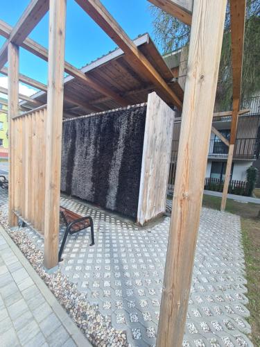 a bench sitting under a wooden pergola at Modrzewiowy Zakątek in Augustów