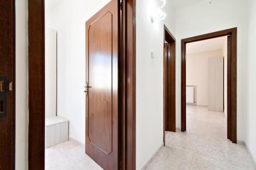 a hallway with a wooden door and a mirror at LuEDa House - Trasfertisti e Turisti in Surbo