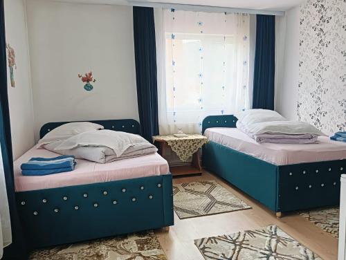 two beds sitting in a bedroom with a window at Casa Emilia in Vatra Dornei