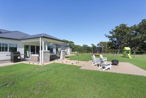 a yard with a house with chairs and a playground at Black Swan Retreat in Metung