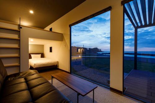 ein Zimmer mit einem Sofa und einem Bett sowie einem großen Fenster in der Unterkunft Oruga Resort -Trailer Cottage & Cafe - in Sakai