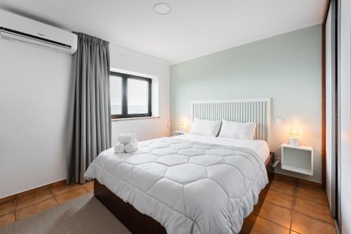 a bedroom with a large white bed and a window at Casa Letrigo in Arcos de Valdevez