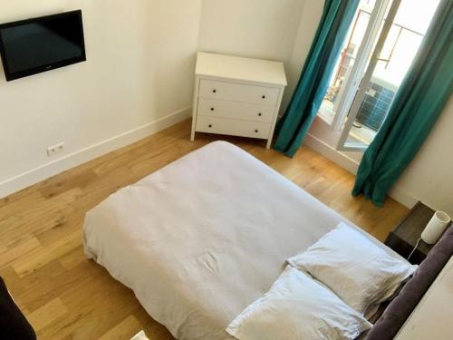 un lit blanc dans une chambre avec une fenêtre dans l'établissement Superbe appartement en plein centre de Cannes, à Cannes