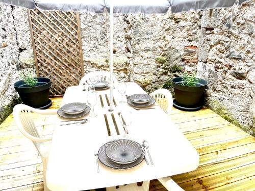 une table et des chaises blanches sur une terrasse en bois dans l'établissement Appartement avec terrasse au coeur d'Aurillac, à Aurillac