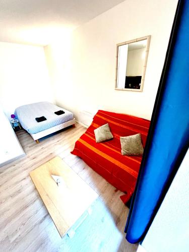 - un salon avec un canapé rouge et un lit dans l'établissement Appartement avec terrasse au coeur d'Aurillac, à Aurillac