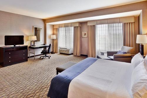 a hotel room with a large bed and a desk at Holiday Inn Detroit Metro Airport by IHG in Romulus