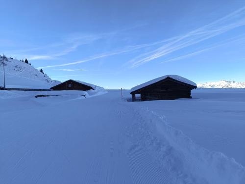 a snow covered field with two buildings in the distance at Ferienwohnung Parsenn Peaks Panorama in Davos