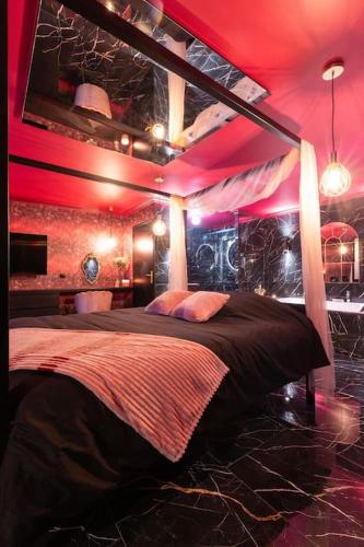 - une chambre avec un grand lit et un éclairage rouge dans l'établissement L'Evidence, à Magny-le-Hongre
