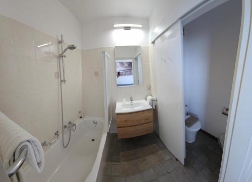 a bathroom with a sink and a tub and a toilet at Hotel Westendia and Free Parking Top Breakfast in Middelkerke