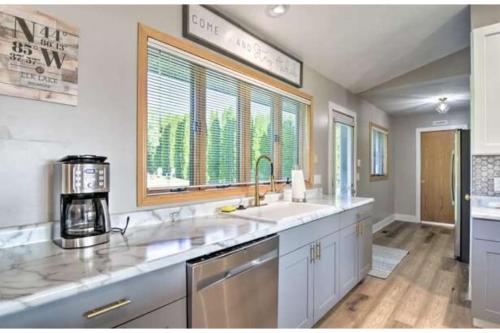 uma cozinha com dois lavatórios e uma grande janela em Beautifully Appointed Elk Lake View Home - Steps from the Lake em Williamsburg