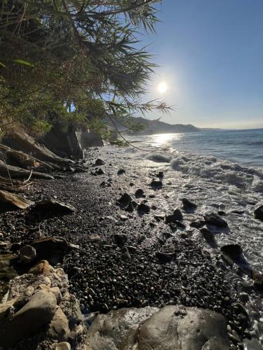 a rocky beach with the sun in the background at Appartamento un mare di fiori in Ventimiglia