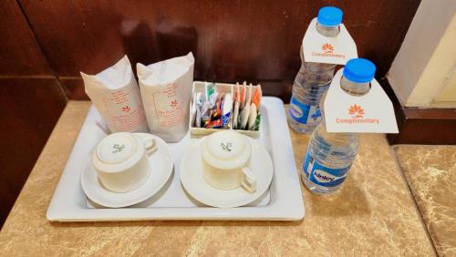 a tray with cups and plates and bottles of water at Hotel The Prime Balaji Deluxe, City Centre, With Free Airport Pickup in New Delhi