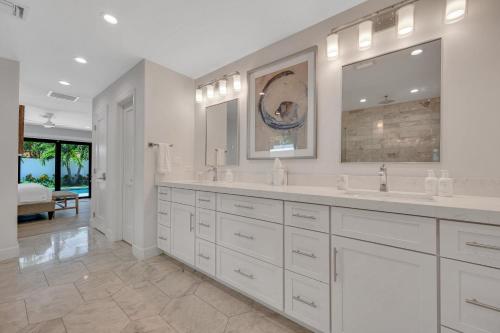 a white bathroom with two sinks and a large mirror at Coastal Style Haven Beach Proximity Heated Pool Tranquility Manatee Ranch Key RESlDENCES in Fort Lauderdale