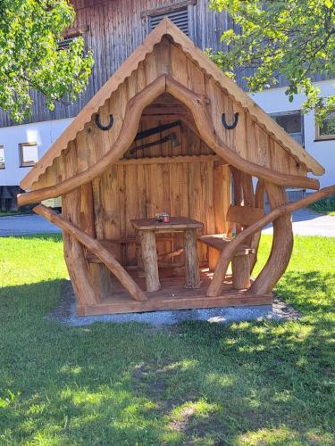 a wooden dog house with a table in the grass at Appartement Höllwarthof in Goldegg