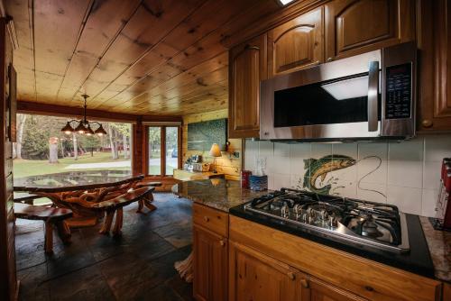 een keuken met een fornuis en een magnetron bij Grayling Gem Royal Stag Serene 6BDR Lodge 5605 in Grayling
