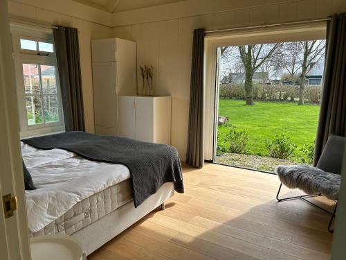 a bedroom with a bed and a large window at Villa Nieuwland B&B in Den Oever