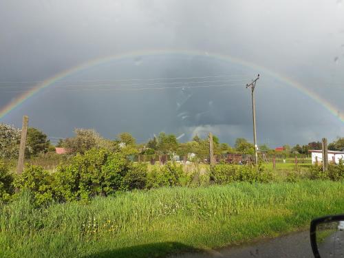 a rainbow in the sky over a field at Paulo in Golenice