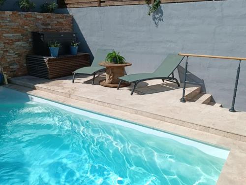 une piscine avec deux chaises et une table dans l'établissement Maison vue sur mer avec piscine, à Port-Vendres