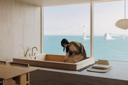 a woman sitting in a bath tub in a bathroom at Onyouji Stay in Busan