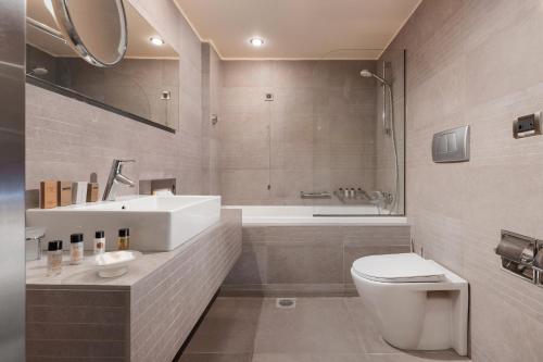 een badkamer met een toilet, een wastafel en een bad bij Kos Aktis Art Hotel in Kos-stad