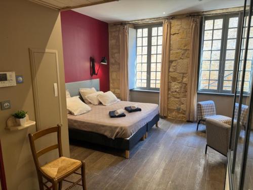 a bedroom with a bed and two windows and a chair at Le STUDIO DUO CITE MEDIEVAL SARLAT in Sarlat-la-Canéda
