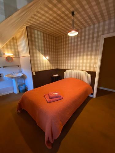 a bedroom with a bed with an orange blanket at Hôtel de famille L.F.M.A.L. in Giat