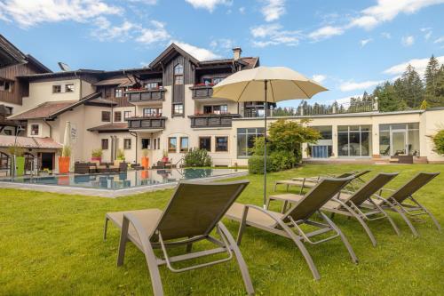 Alpen Adria Hotel & Spa في بريسيغ: مجموعة كراسي ومظلة أمام المنزل