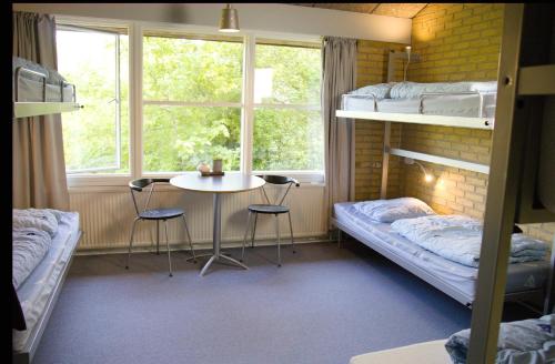 een slaapzaal met stapelbedden en een tafel en stoelen bij Danhostel Horsens in Horsens