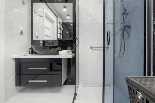 uma casa de banho com um lavatório e um chuveiro em Jantar Apartamenty - Miodowy Dom City Center em Kolobrzeg