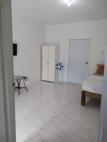 a white room with a bedroom with a bed and a table at Hill View Rooms in St Mary
