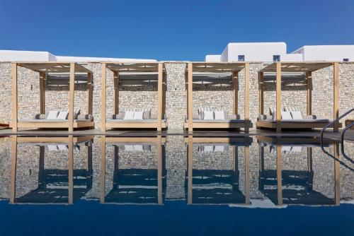 a building with white chairs on the water at Kosmoplaz Beach Hotel in Platis Gialos