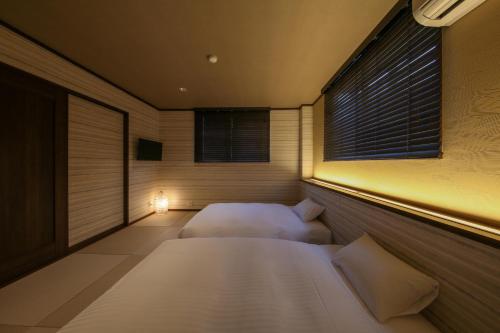 a bedroom with two beds and a window at ROMANSTAY in Takayama