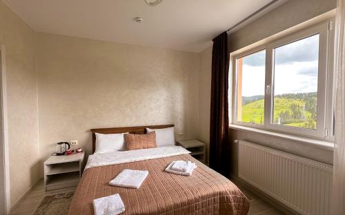 a bedroom with a bed and a large window at Шепіт Лісу in Bukovel