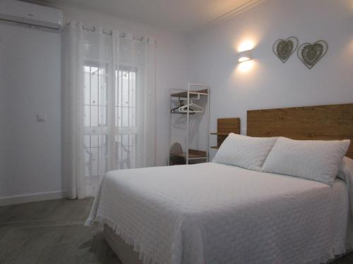 Habitación blanca con cama y ventana en APARTAMENTO SOL en Chipiona