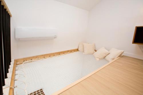 a room with a white couch with pillows on it at Montsejour - T2 climatisé avec filet et fauteuil suspendu in Tarbes