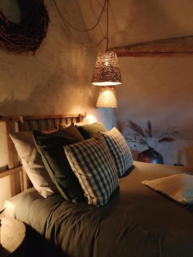 - une chambre avec un lit doté d'oreillers et d'une lampe dans l'établissement La lande sèche, à Lainsecq