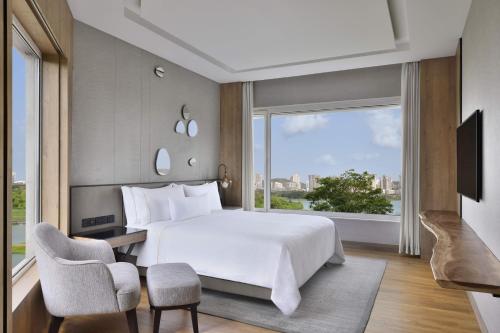 um quarto com uma cama grande e uma janela grande em The Westin Mumbai Powai Lake em Mumbai