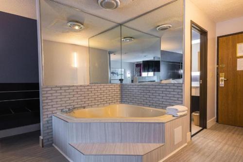 a large bathroom with a tub with a large mirror at Coratel Inn & Suites by Jasper Hastings in Hastings