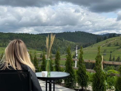 una mujer sentada en una mesa mirando un valle en Шепіт Лісу en Bukovel